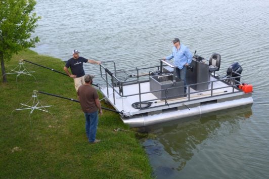 Group of men standing on a pontoon boat getting ready to electrofish