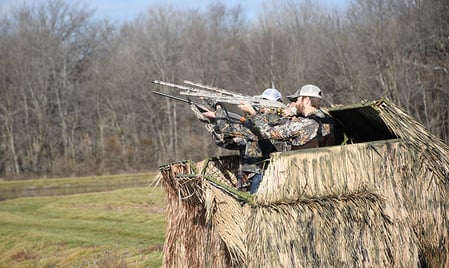 hunters standing in duck blind ready to shoot