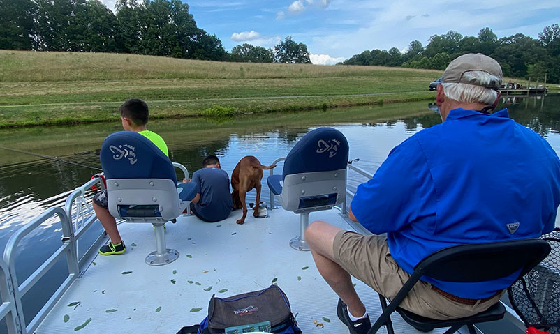 family and dog fishing on pontoon